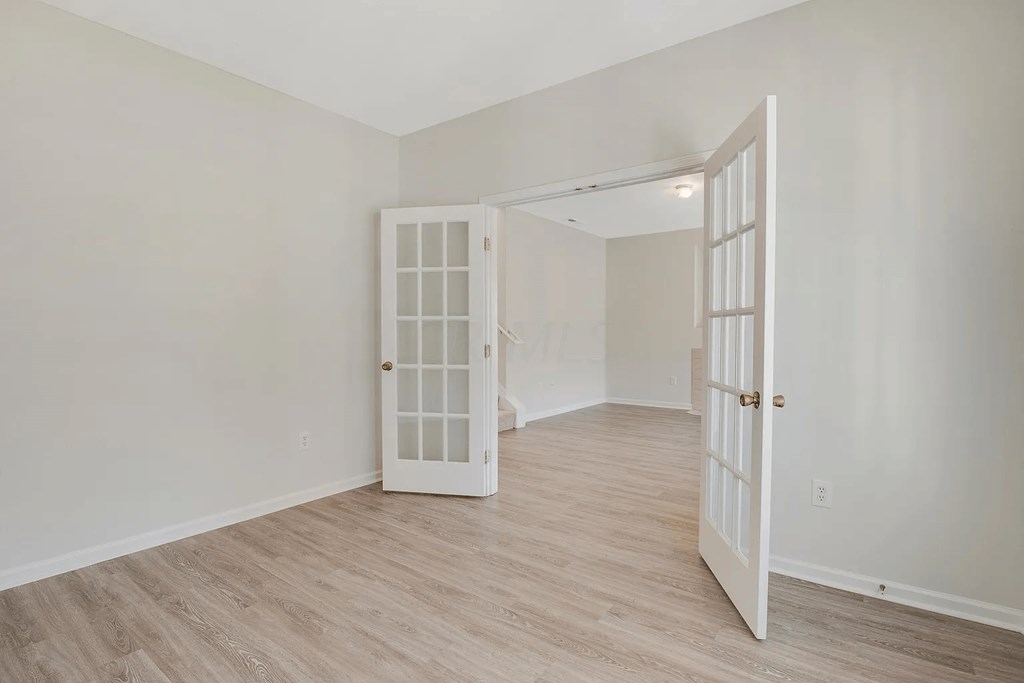 a bedroom with an open door and a wood floor