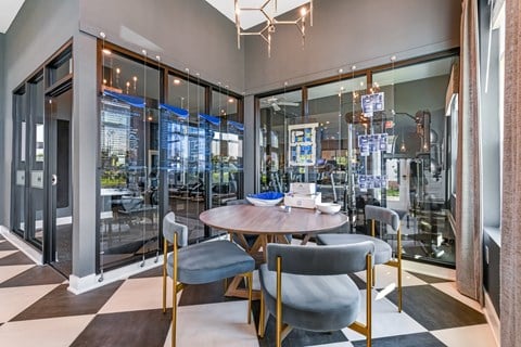 A modern dining room with a round table and grey chairs.