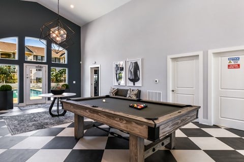 A pool table in a room with a black and white checkered floor.