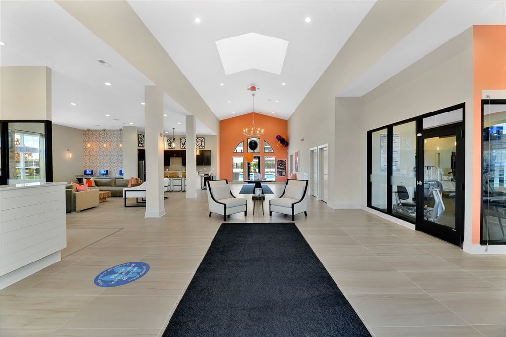 A spacious lobby with a black carpet leading to a white reception desk.