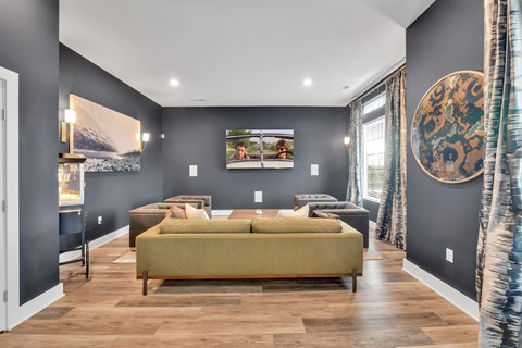 A living room with a green sofa and a painting on the wall.