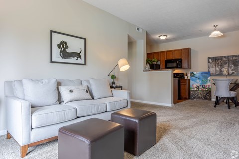 A living room with a white couch and a brown ottoman.