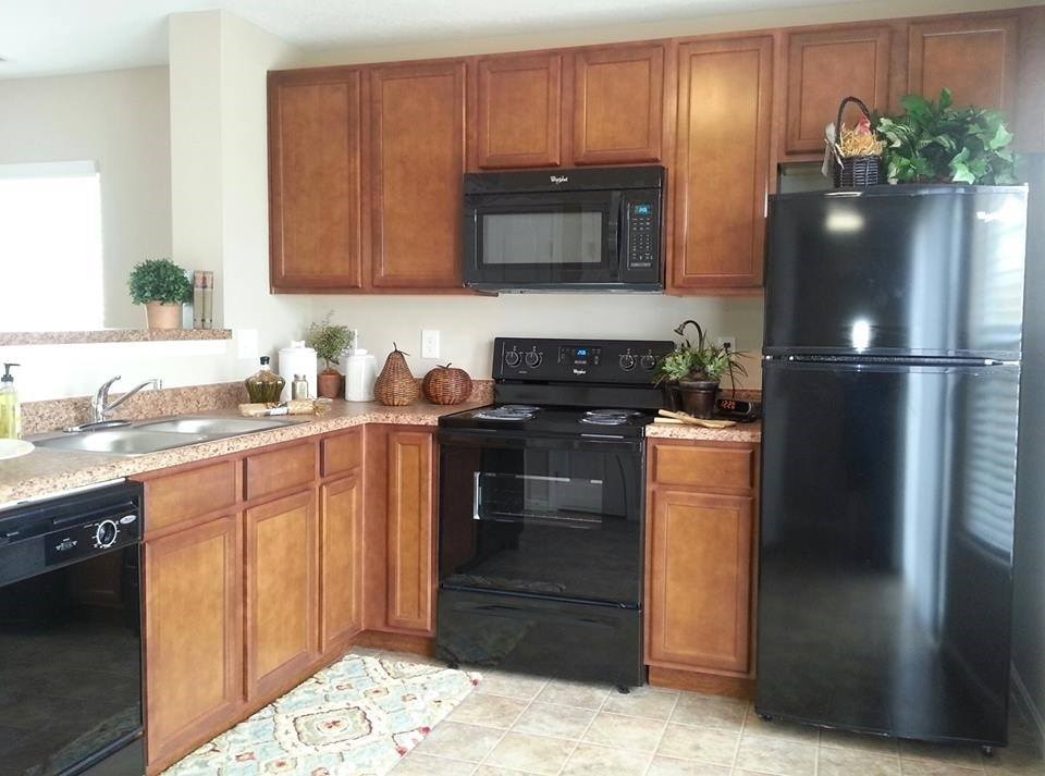 A kitchen with black appliances and wooden cabinets.