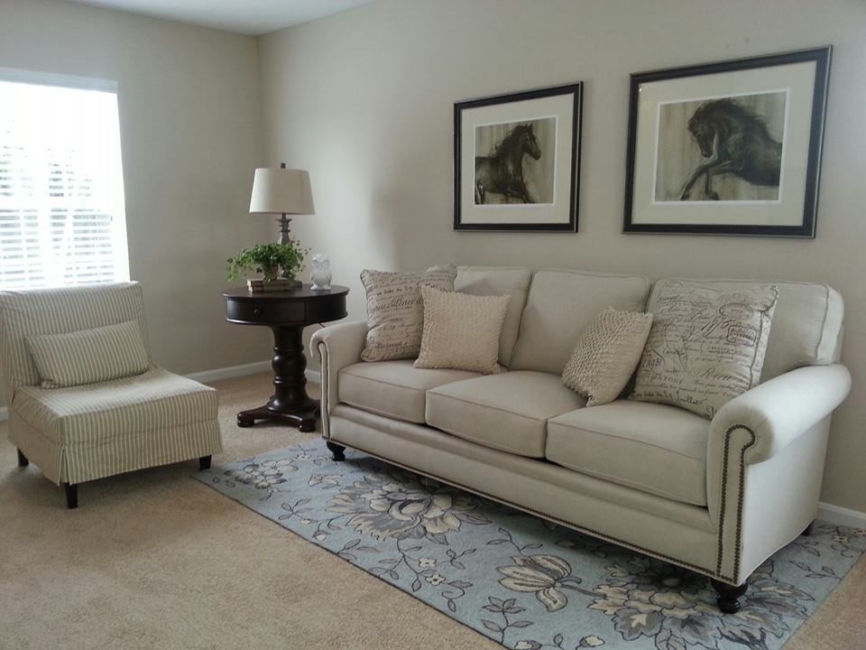 A living room with a couch, chair, and two framed pictures on the wall.