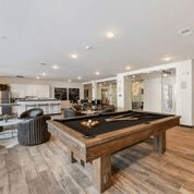 A pool table is in the middle of a room with a wooden floor.
