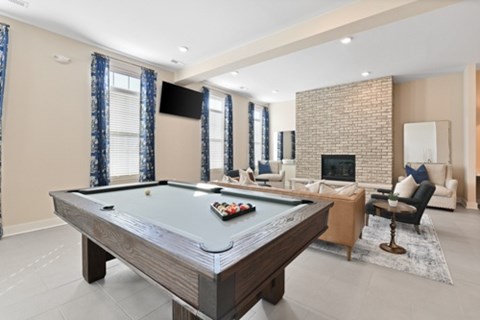 A pool table is in the middle of a room with a fireplace and a couch.
