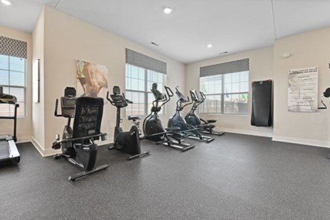 A gym with a variety of exercise equipment including treadmills, stationary bikes, and elliptical machines.