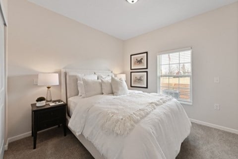 A bedroom with a large bed and a nightstand with a lamp.