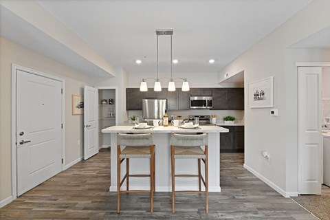 A modern kitchen with a dining table and chairs in the middle.