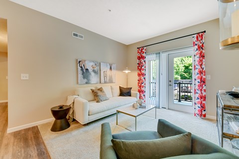 A living room with a white couch and a painting on the wall.