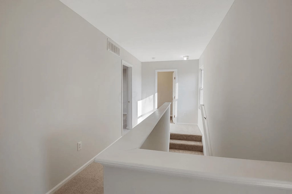 a white room with stairs and a hallway with a door