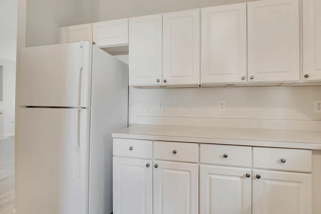 a white kitchen with white cabinets and a refrigerator
