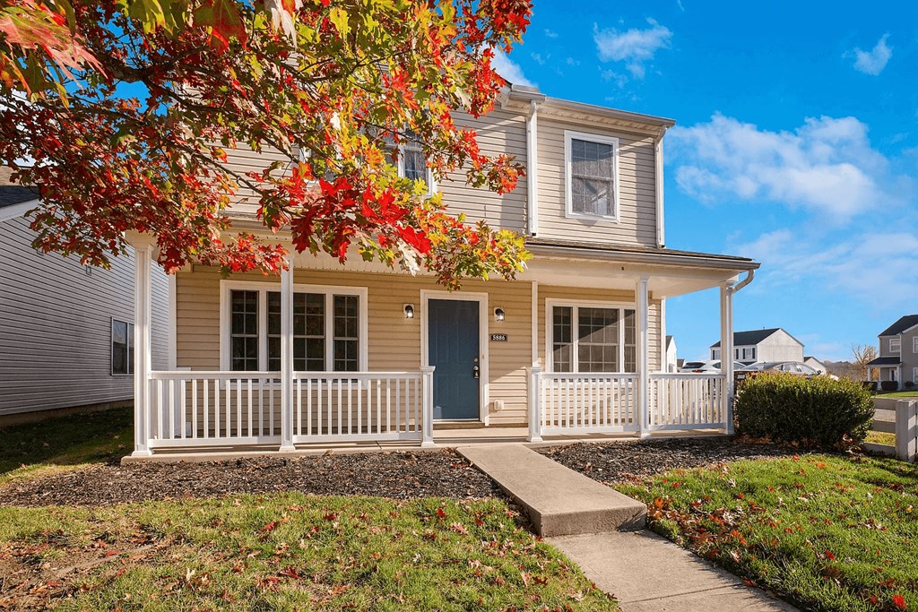 a tan house with a white porch and a blue door