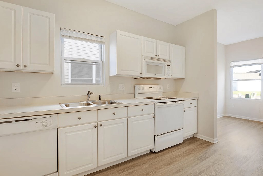 a kitchen with white cabinets and appliances and a window