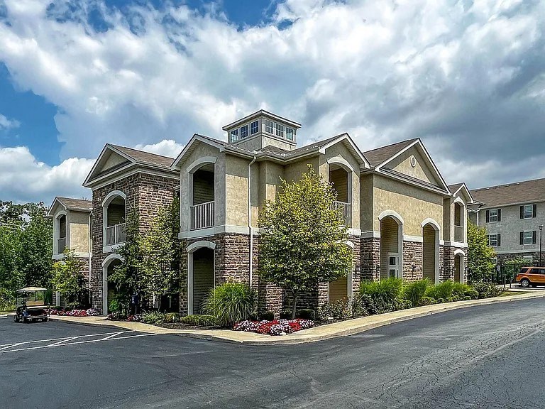 a large house with a street and a cloudy sky