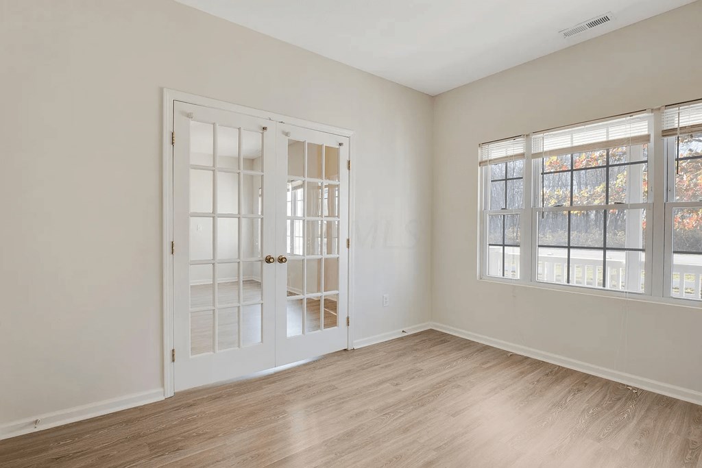 a living room with white walls and doors and wood floors