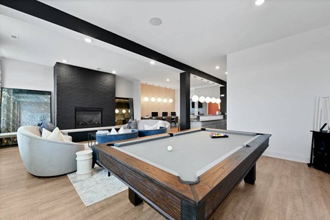 A pool table is in the middle of a room with a fireplace and a chair.