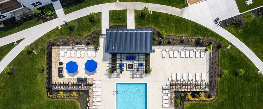 A swimming pool is surrounded by a deck and a small building.