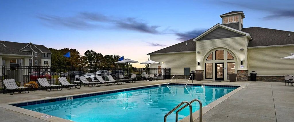 a swimming pool with chairs next to a building