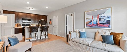 A living room with a grey couch and a painting on the wall.