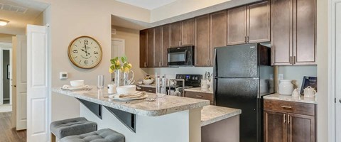 A kitchen with a black refrigerator and brown cabinets.