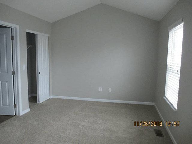 A room with a carpet floor, a door, and a window.
