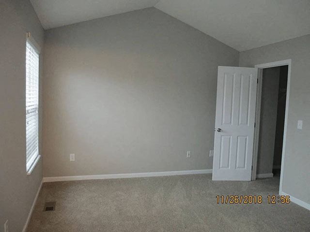 A room with a white door and a window with blinds.