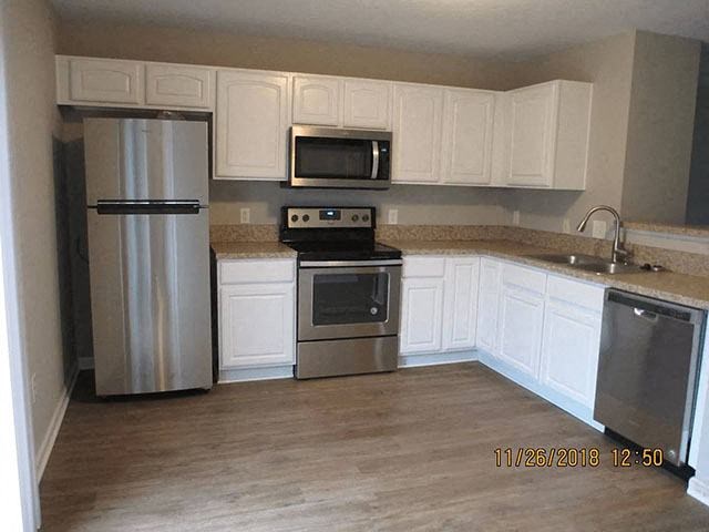 A kitchen with a stainless steel refrigerator, microwave, oven, and sink.