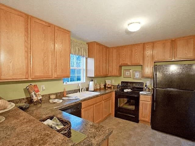 A kitchen with wooden cabinets and a black refrigerator.