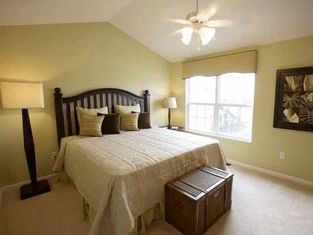 A bedroom with a bed, nightstand, and window.
