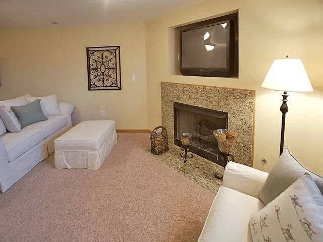 A living room with a fireplace and a television mounted above it.