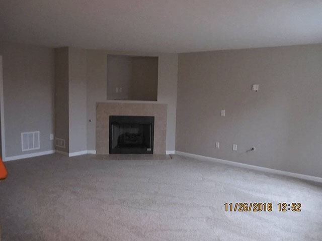 A room with a fireplace and carpeting on the floor.