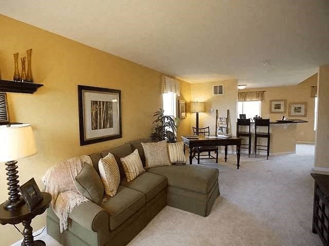 A living room with a couch, a table, and a lamp.
