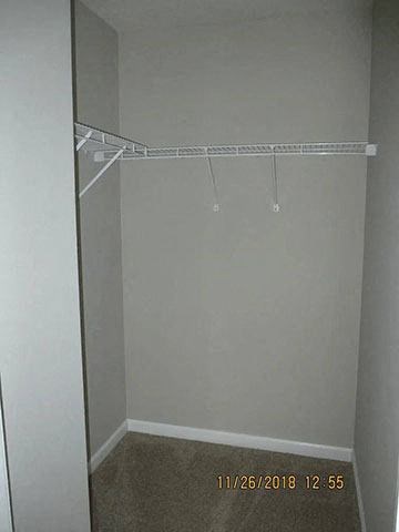 A small, empty closet with a shelf and a date stamp on the floor.