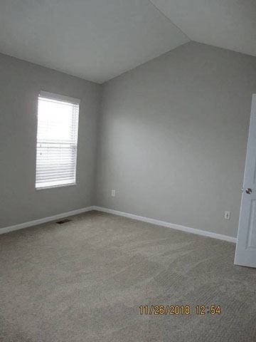 A room with a window and carpeted floor.