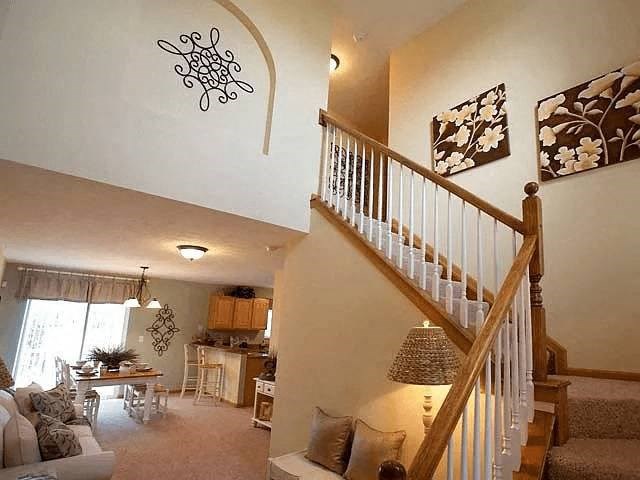 A living room with a staircase and a dining area.