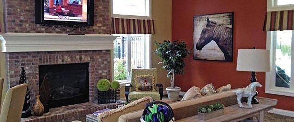 A living room with a fireplace and a painting of a horse on the wall.