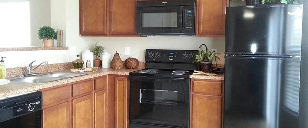 A black refrigerator sits in a kitchen with wooden cabinets.