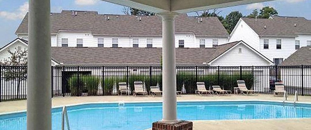 A pool with a white house in the background.