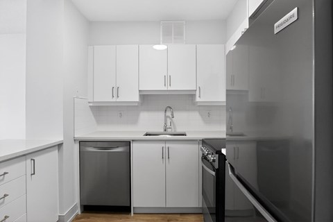 A modern kitchen with white cabinets and stainless steel appliances.