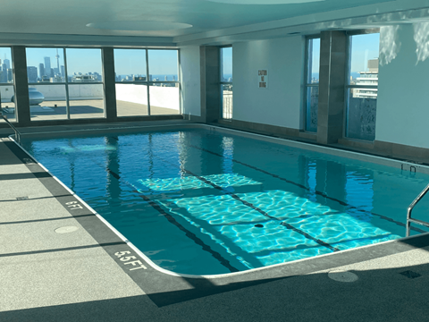 A rectangular indoor swimming pool with a glass wall on one side.