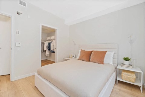 A bedroom with a large bed and a small table with a plant on it.