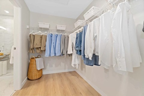 a closet with a rack of clothes and a basket on the floor