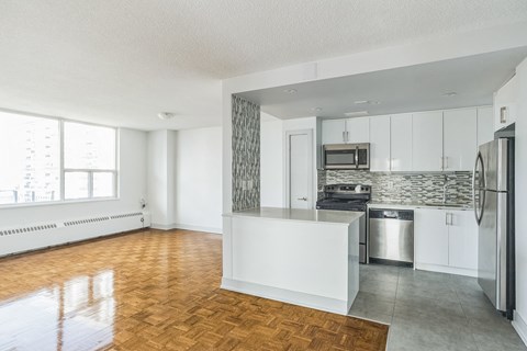 A kitchen with white cabinets and a wooden floor.