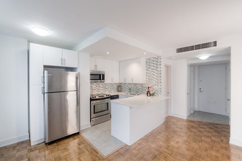 a kitchen with white cabinets and a stainless steel refrigerator