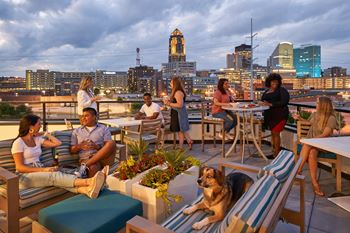 A group of people are sitting on a rooftop terrace with a city skyline in the background.at Linc, Des Moines, IA  