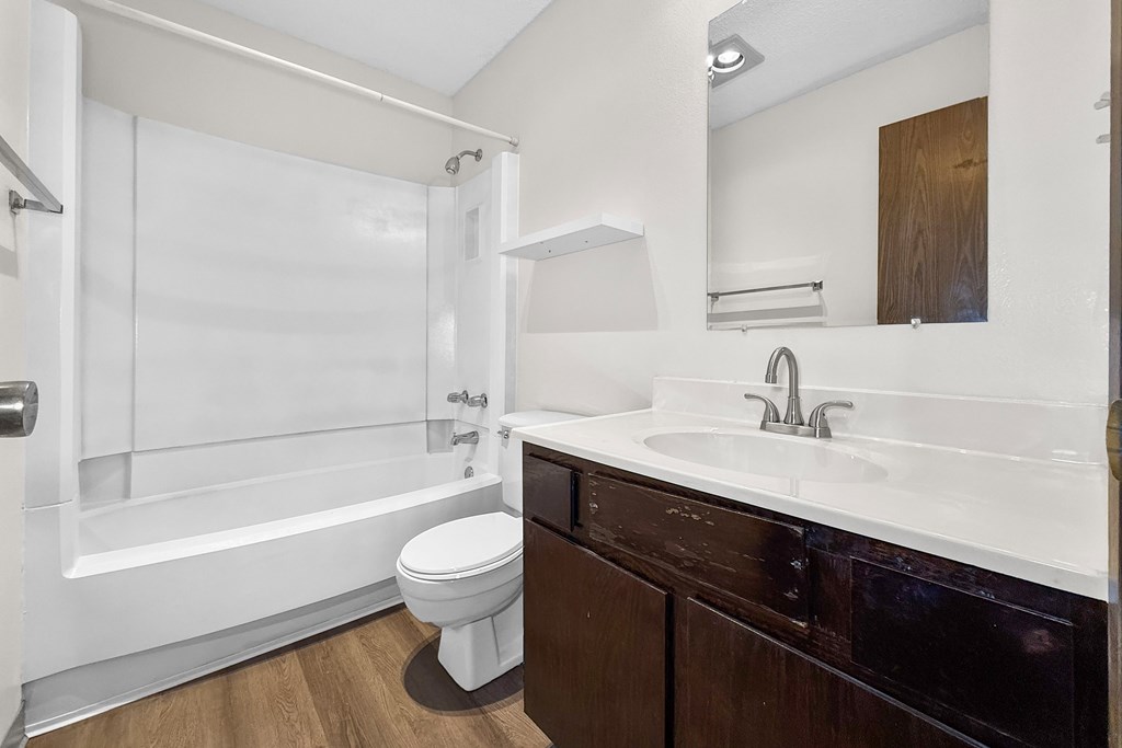 A white toilet sits in a bathroom with a white tub and sink.