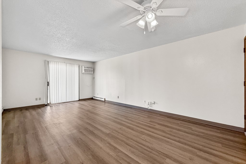 A room with a ceiling fan and wooden flooring.