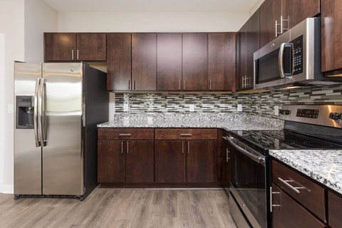 A kitchen with a stainless steel refrigerator and wooden cabinets.