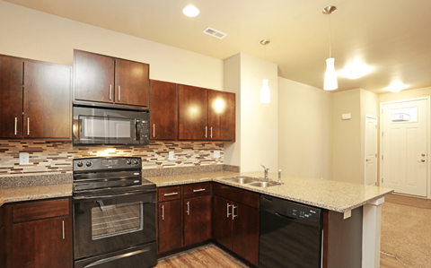 A kitchen with dark wood cabinets and black appliances.